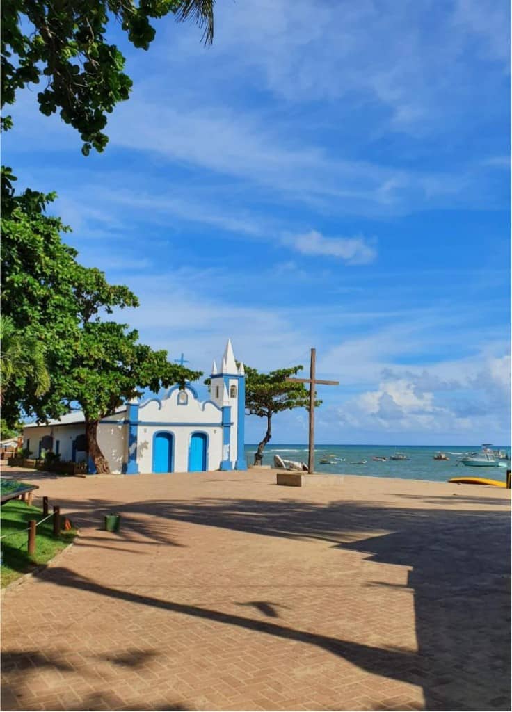 Capela de São Francisco de Assis na Praia do Forte, com o mar e barcos ao fundo