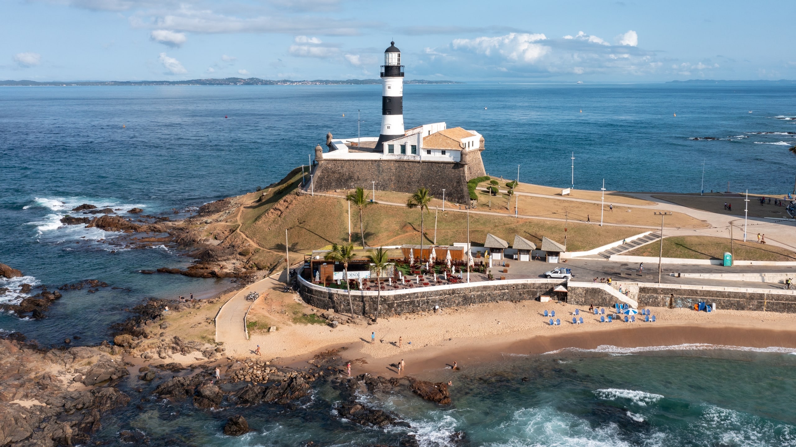 Vista aérea do Farol da Barra e do Forte de Santo Antônio da Barra, com praia e mar ao redor